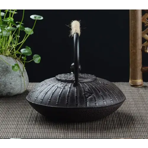Close-up of bamboo design engraving on matte black cast iron teapot surface