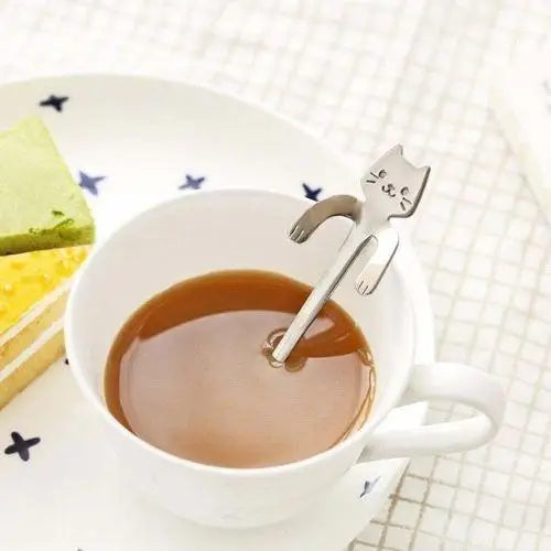 Cat tea spoon being used to stir tea in a ceramic mug