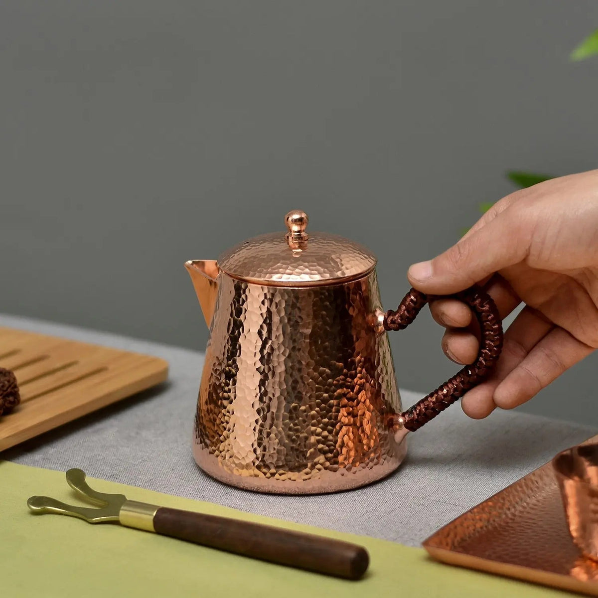 Copper teapot for loose leaf tea with steam rising, cozy setting