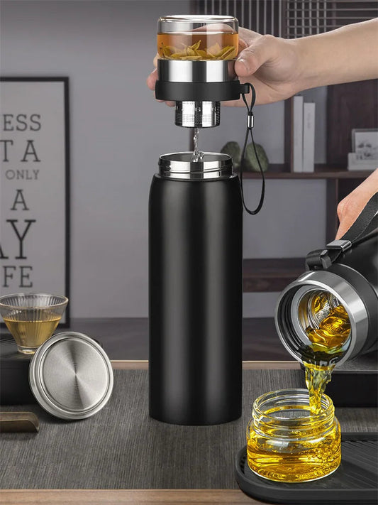 Stainless steel insulated teapot with steam rising from the spout, loose-leaf tea brewing inside