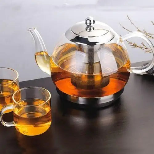 Clear glass teapot filled with brewed tea on a wooden tray