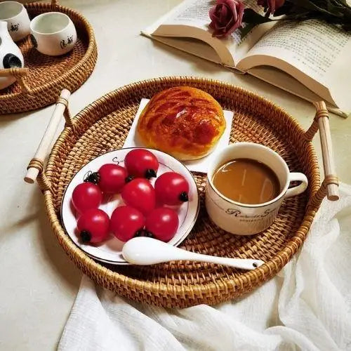 Round wicker tea tray with wooden handles on a table