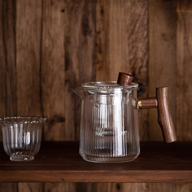 Teapot in glass with tea leaves unfurling in hot water