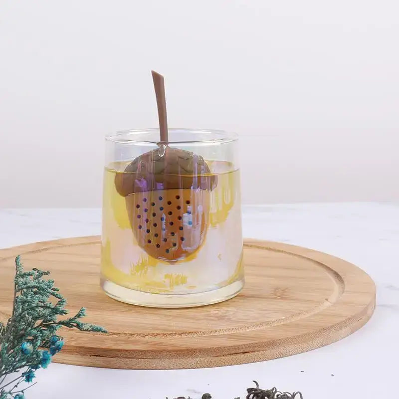 Acorn tea infuser on a wooden table with tea cup