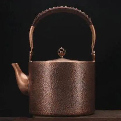 Handcrafted copper tea kettle steaming on a wooden table