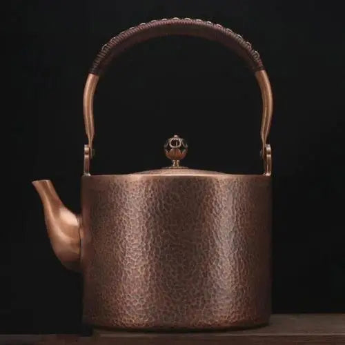 Handcrafted copper tea kettle steaming on a wooden table