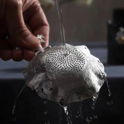 Cleaning antique tea strainer under water