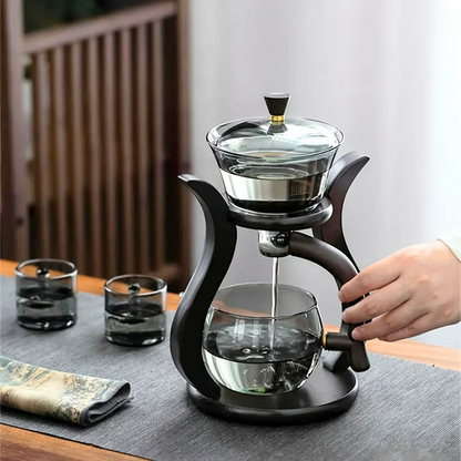 Automatic tea infuser glass teapot with loose leaf tea leaves nearby
