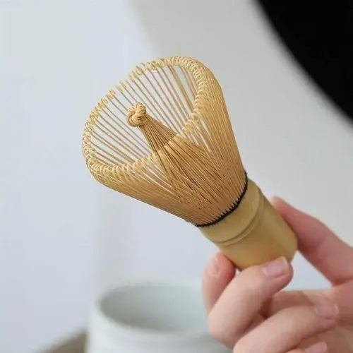 Natural white bamboo matcha whisk resting on wooden surface