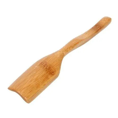 Bamboo wood tea spoon laid flat on a wooden surface