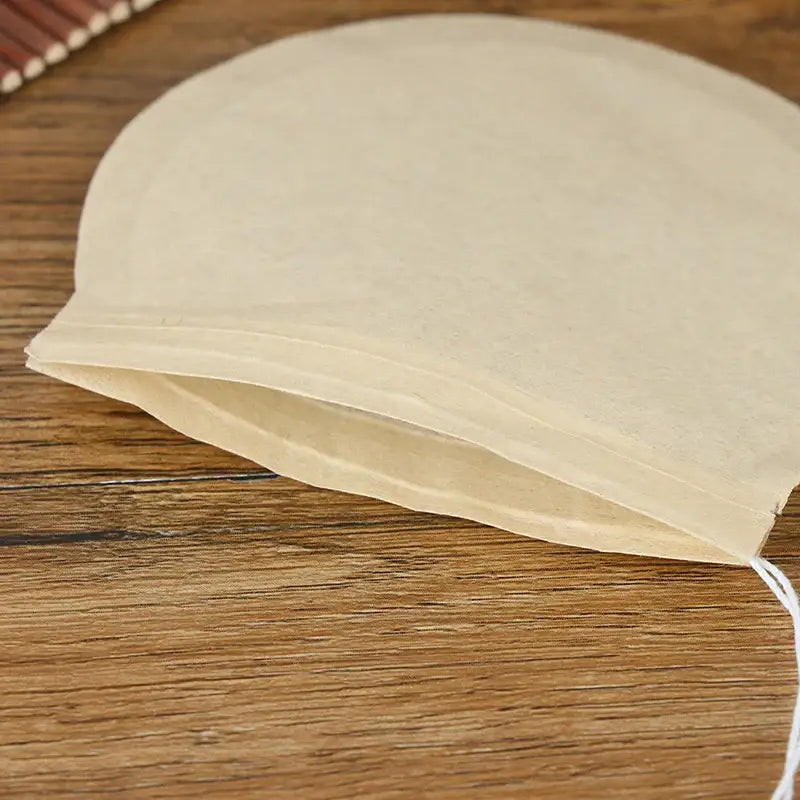 Tea filter bag filled with loose-leaf tea, drawstring pulled closed
