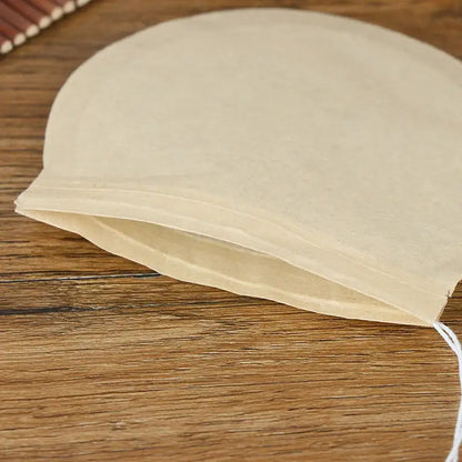 Tea filter bag filled with loose-leaf tea, drawstring pulled closed