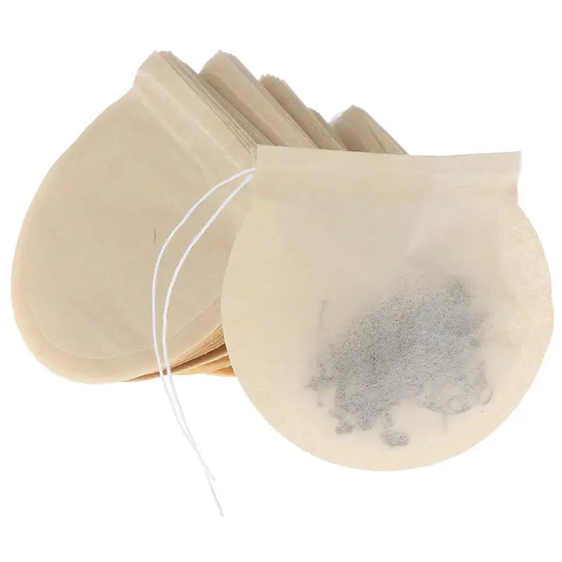 Biodegradable tea filter bag steeping in a glass mug, warm light