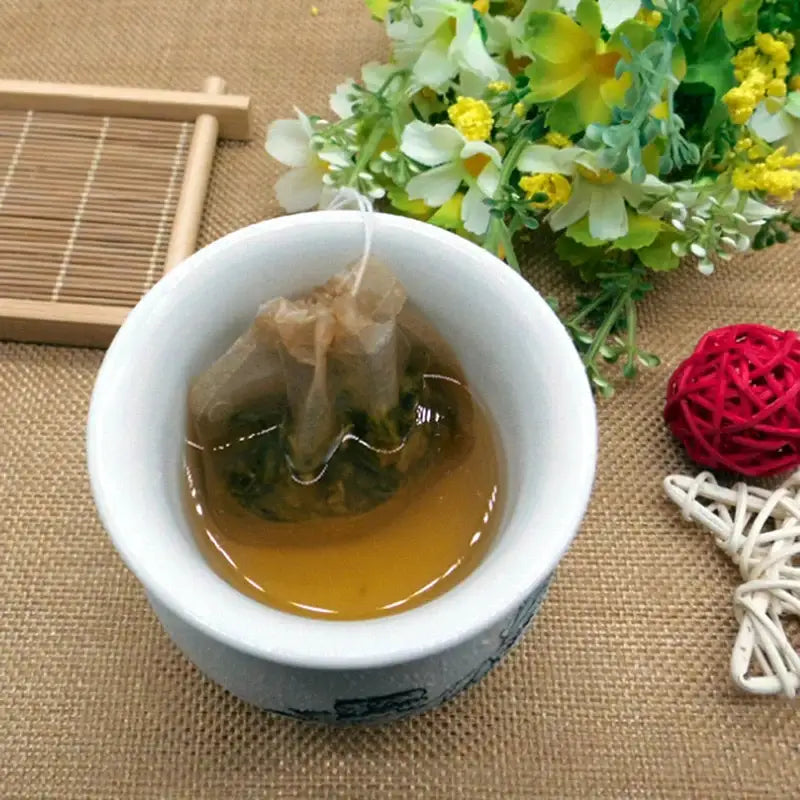 Biodegradable tea filter bag holding green tea leaves, top-down view