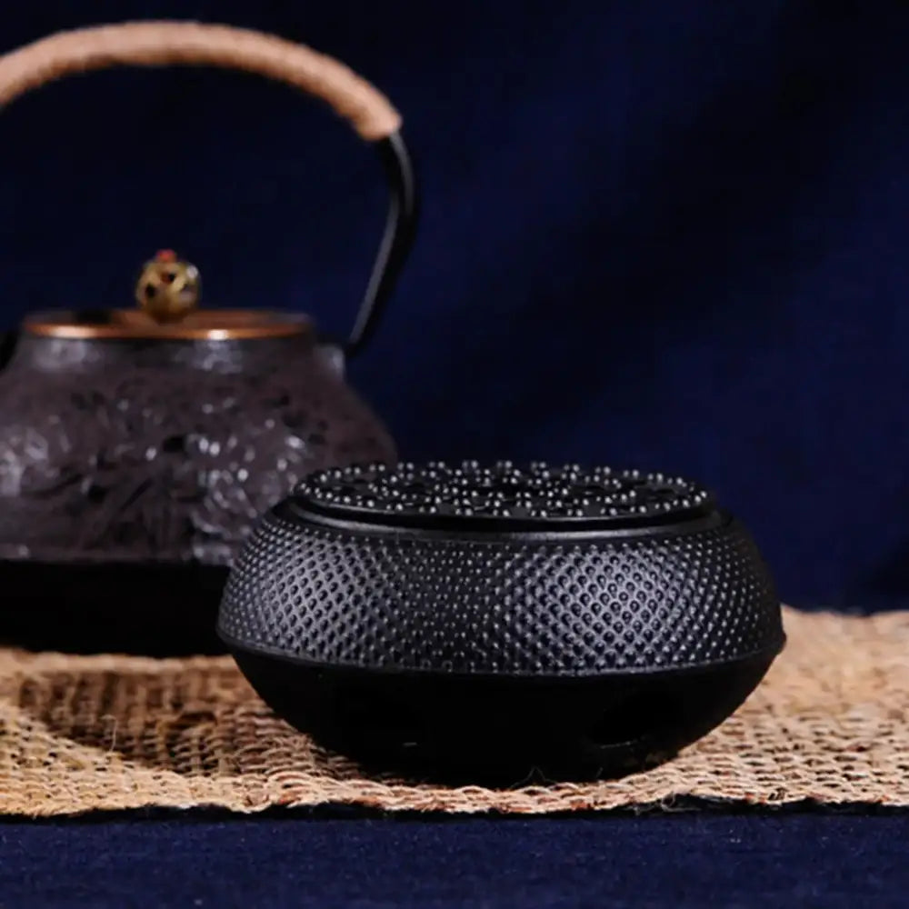Ventilated cast iron teapot warmer with a lit tea light candle inside
