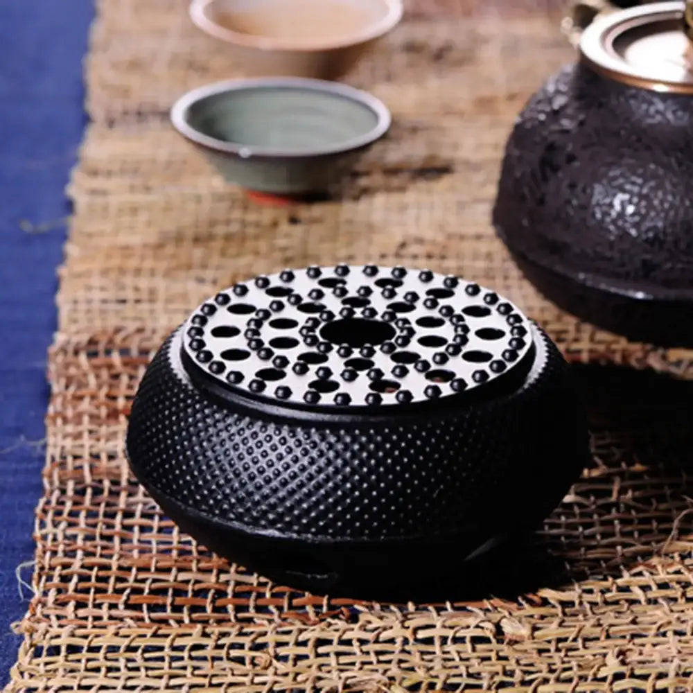 Cast iron teapot warmer supporting a ceramic teapot during a tea session