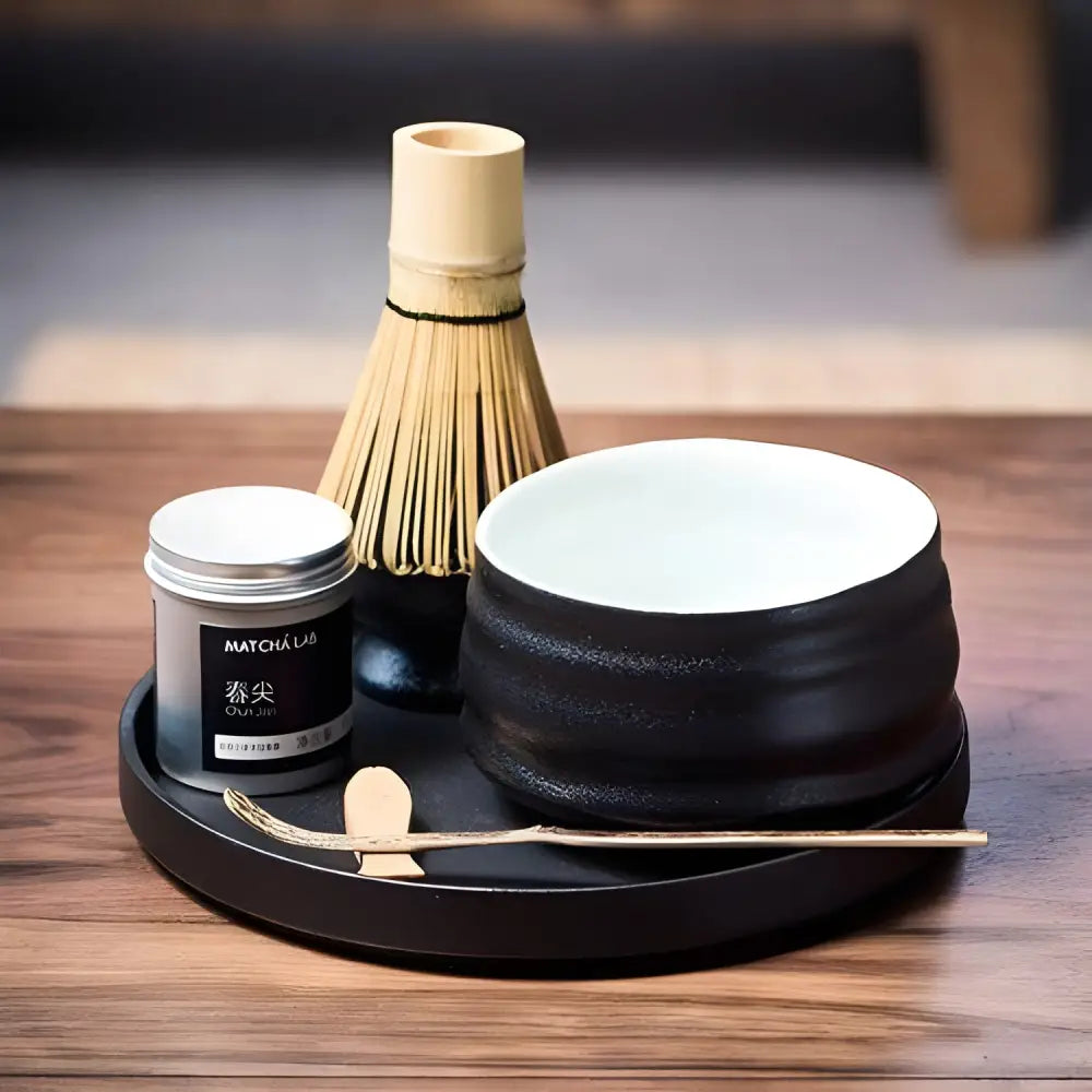 Black chawan matcha bowl shown with tea accessories on table