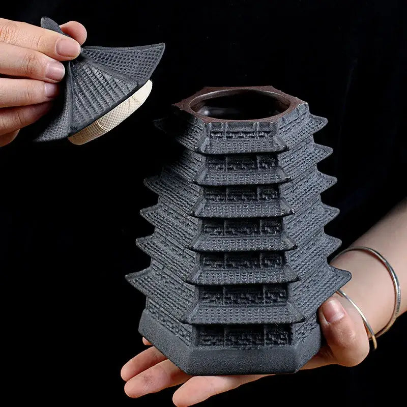 Black ceramic tea canister with fitted lid and temple design, angled view