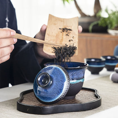 Blue enameled teapot pouring tea into gaiwan, gongfu-style brewing