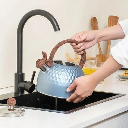 Pouring water from blue whistling tea kettle