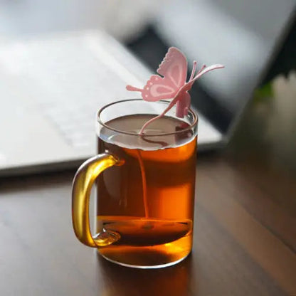 Pink butterfly tea infuser in a white ceramic mug