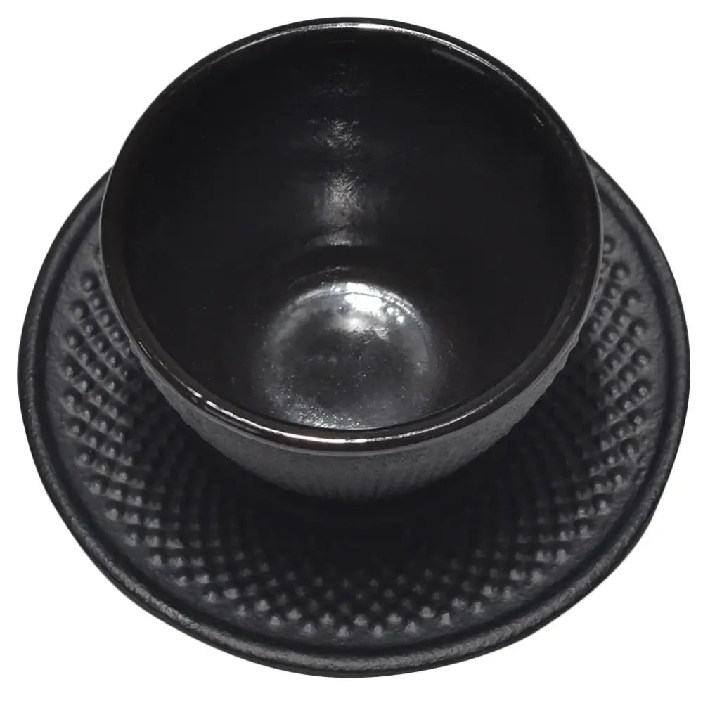 Black cast iron tea cup with matching saucer on wooden table