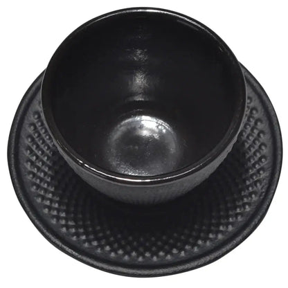 Black cast iron tea cup with matching saucer on wooden table