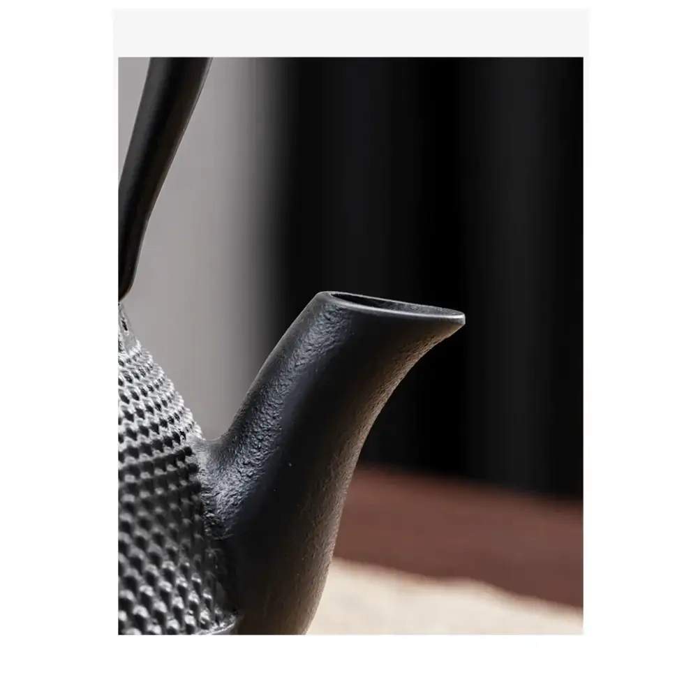 Cast iron teapot beside a cup of brewed tea and loose tea leaves