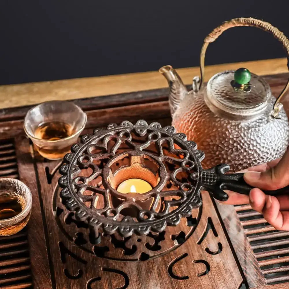 Cast iron tea warmer platform resting on wrought iron stand, side angle view