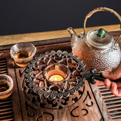 Cast iron tea warmer platform resting on wrought iron stand, side angle view