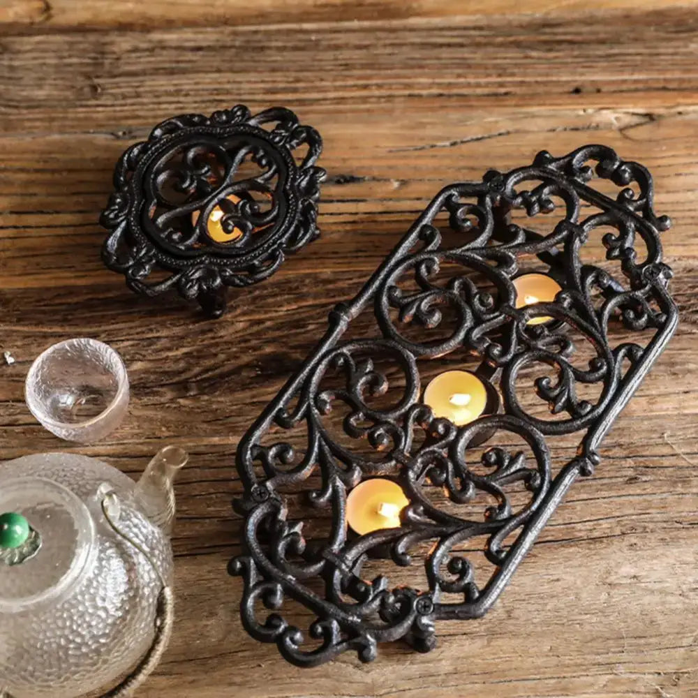 Hand-forged wrought iron tea warmer displayed on wooden table with teapot
