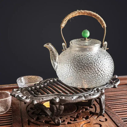 Cast iron teapot warmer with tea light candle lit underneath wrought iron stand