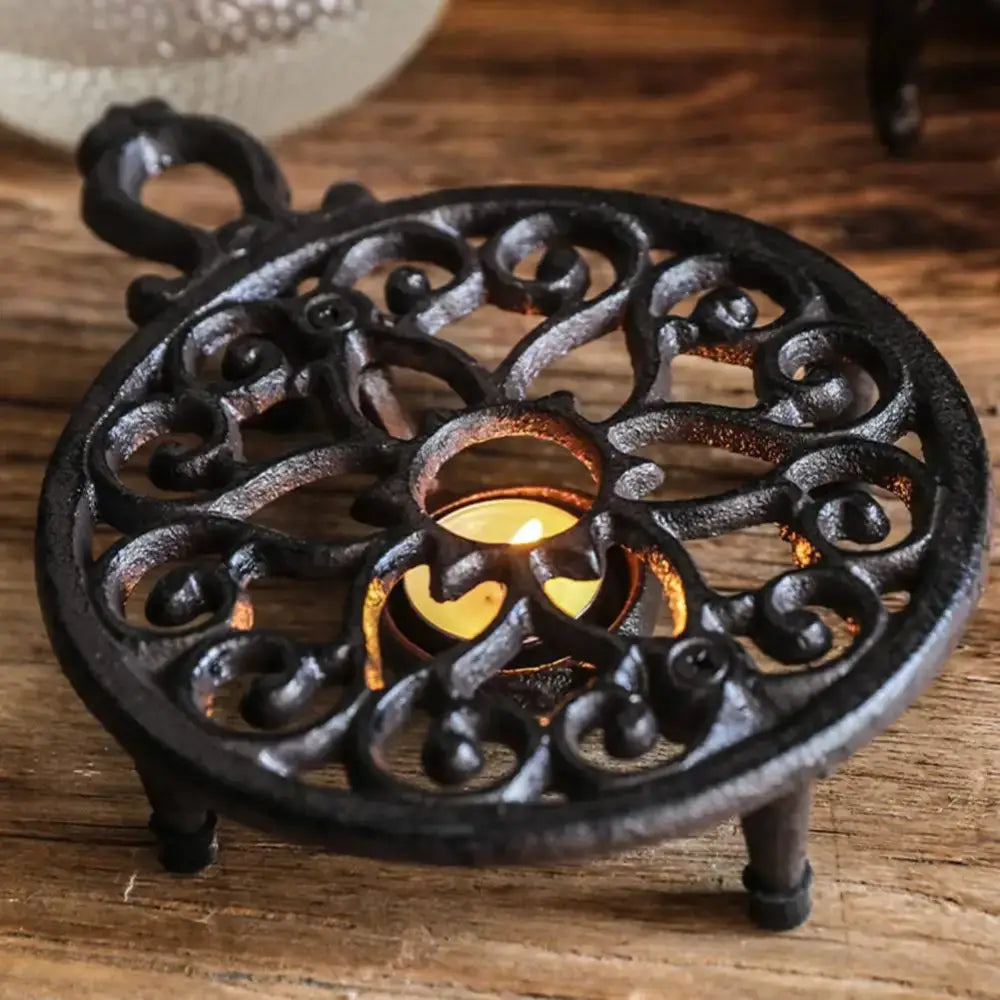 Cast iron tea warmer holding ceramic teapot during serving, warm light setting