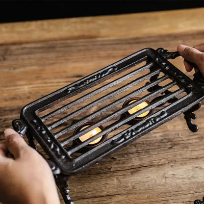 Hand-forged wrought iron teapot warmer stand detail showing forging texture and dark iron finish