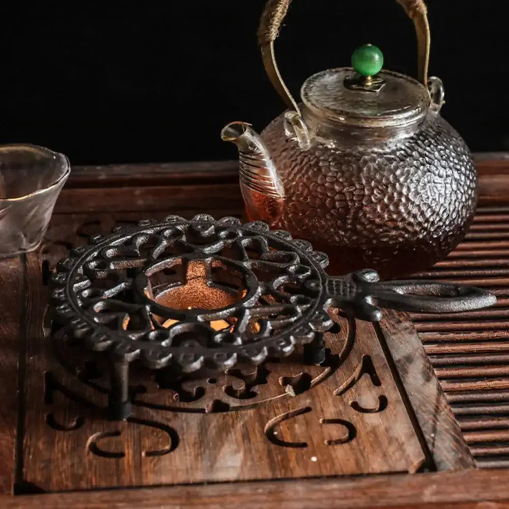 Rustic cast iron tea warmer with wrought iron stand on kitchen counter, cozy morning scene