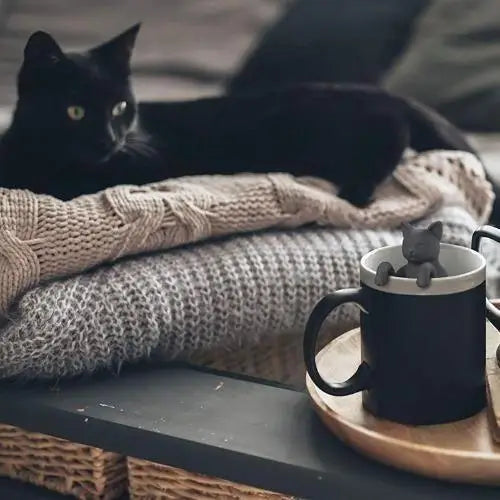 Person using cat tea infuser in a mug