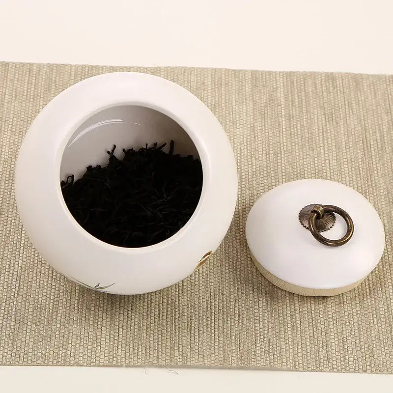 Mountain motif ceramic tea canister with loose leaf tea on countertop