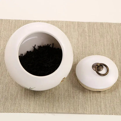 Mountain motif ceramic tea canister with loose leaf tea on countertop
