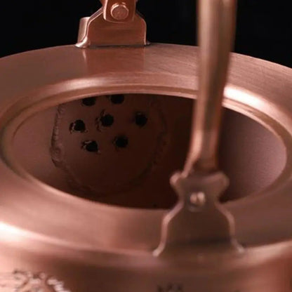Copper teapot with engraved floral pattern, side detail showing motif depth and warm patina