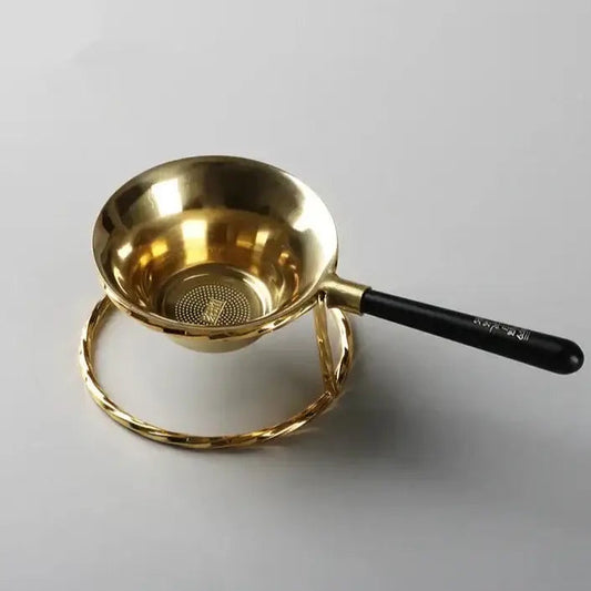 Copper tea strainer with fine mesh resting on a cup