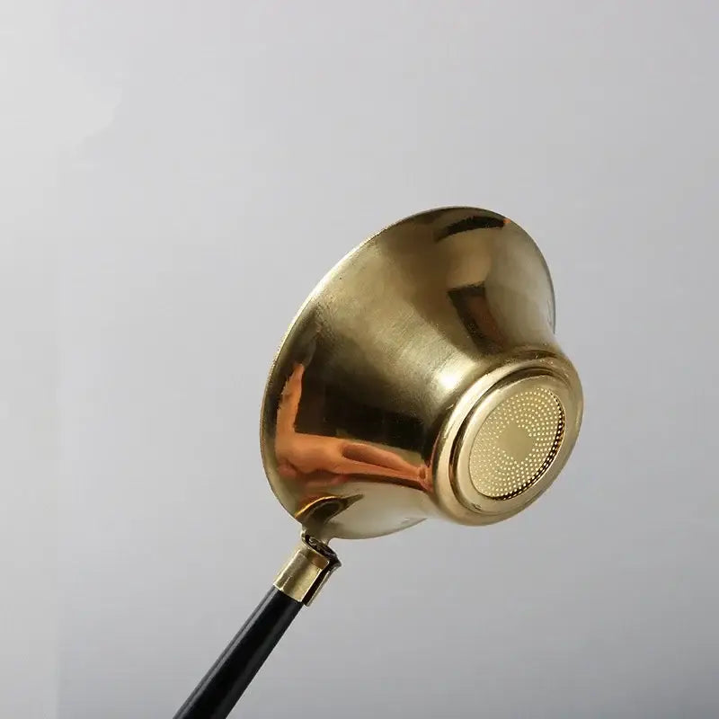 Copper tea strainer with handle on a saucer