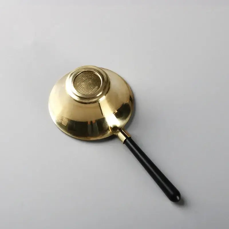 Copper tea strainer pouring tea into a mug