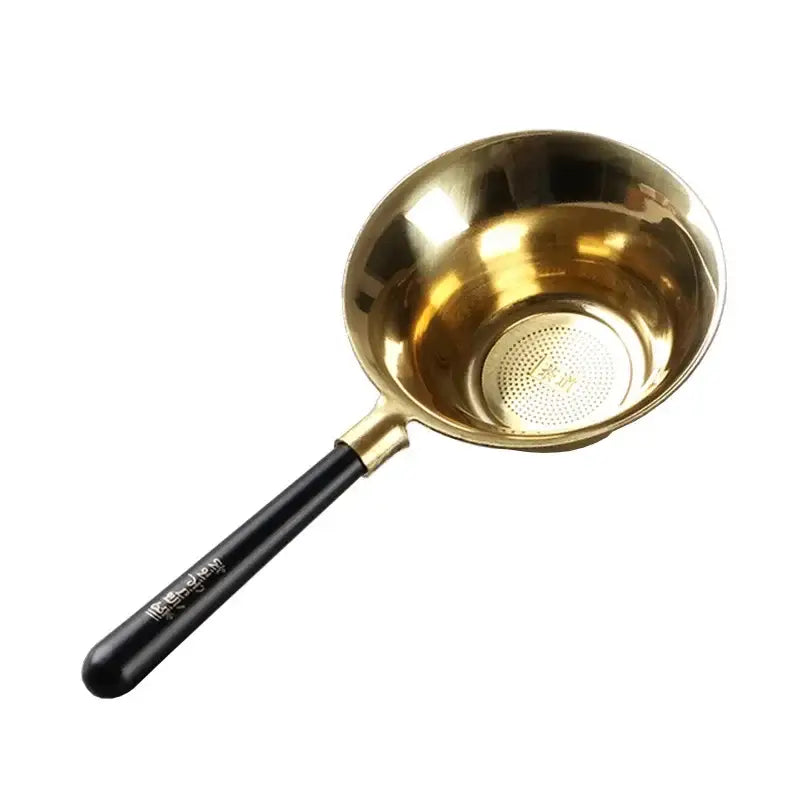 Copper tea strainer with loose leaf tea beside it