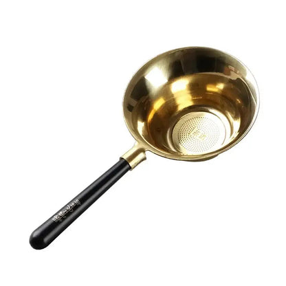 Copper tea strainer with loose leaf tea beside it