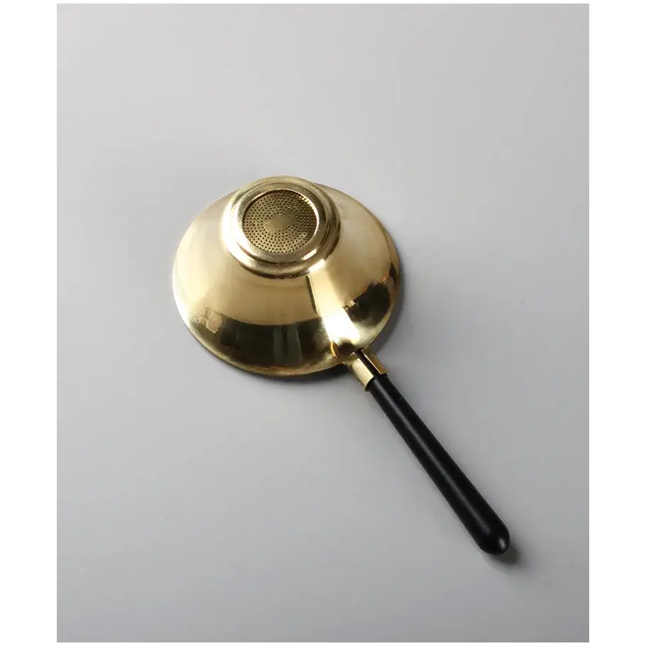 Copper tea strainer with steam rising from cup