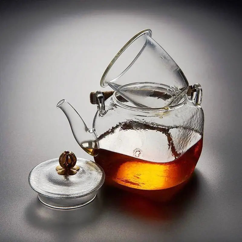 Copper teapot pouring brewed loose-leaf tea into a ceramic cup