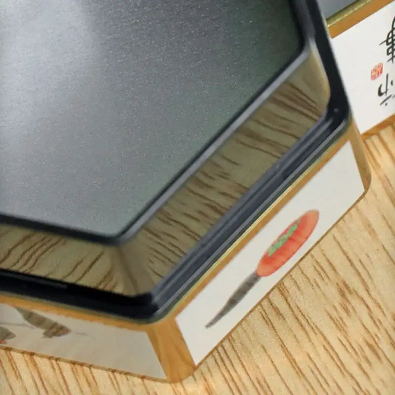 Green decorative tea tin with Chinese painting design on wooden table