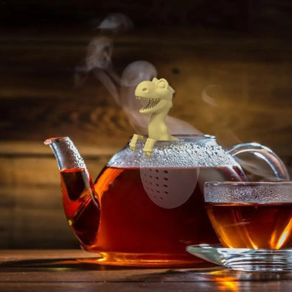 Dinosaur tea infuser resting beside a cast iron teapot on a wooden tray