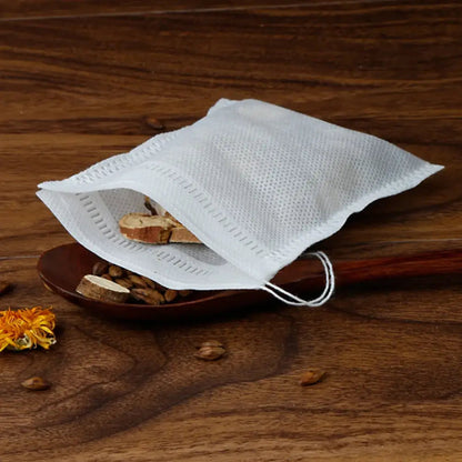 Drawstring tea filter bag with dried chamomile flowers, placed in glass teapot