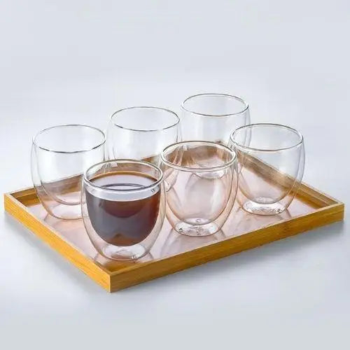 Double wall glass tea cup filled with amber oolong tea, floating effect visible